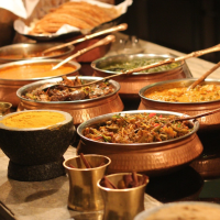 Authentic Indian food spread with curries, naan, and traditional copper serving bowls at Bombay Kitchen and Bar in Vancouver.