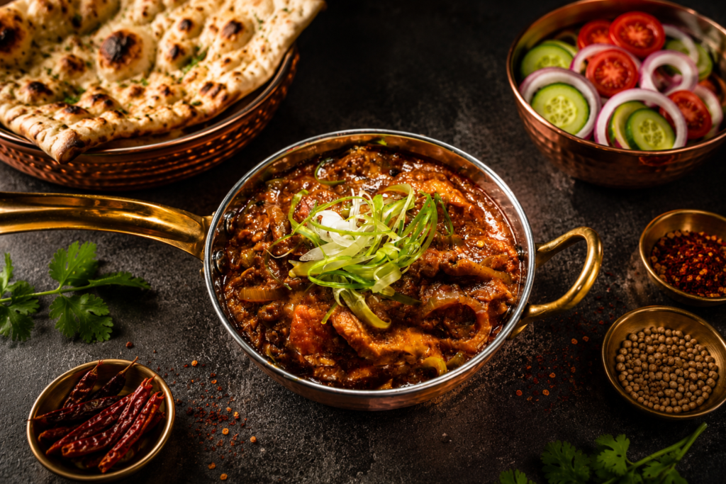 Lamb Combo featuring slow-cooked lamb curry garnished with fresh scallions, served with garlic naan, fresh cucumber and tomato salad, and traditional Indian spices.